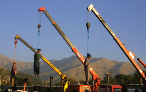TEHRAN, IRAN:  From L to R: Amir Fakhri, Payam Amini, and Majid Ghasemi, sentenced to death, are seen dangling from cranes in east Tehran 29 September 2002. Residents of the Iranian capital were treated to a public display of revolutionary justice, with five convicted gang rapists executed by hanging at dawn at different sites in the capital. AFP PHOTO/Behrouz MEHRI (Photo credit should read BEHROUZ MEHRI/AFP/Getty Images)